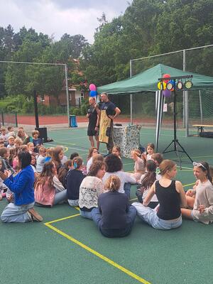 Bild vergr&ouml;&szlig;ern: Kinder sitzen auf dem Sportplatz, ein Lehrer macht eine Ansage